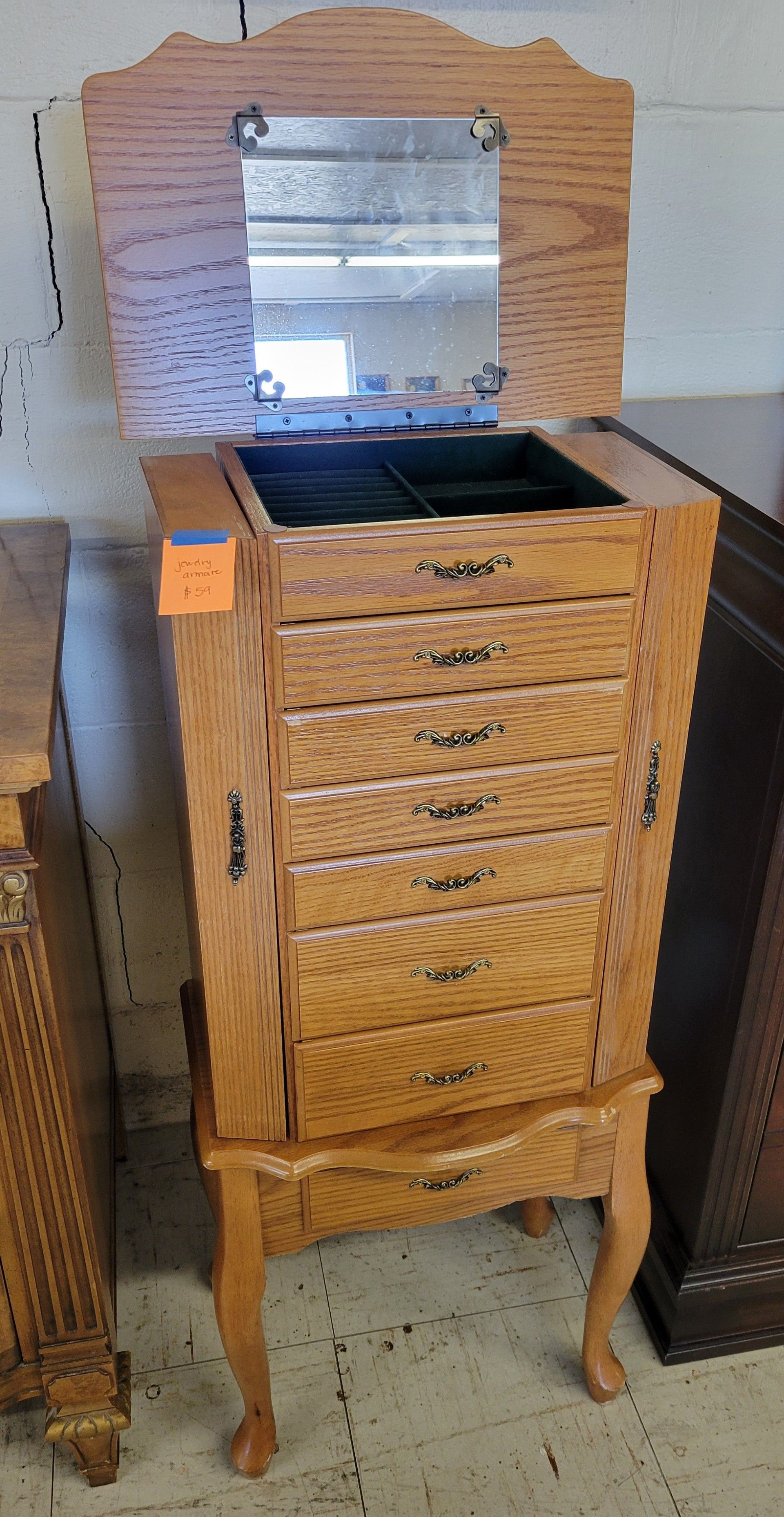 Wooden dresser with attached mirror, brown with decorative carvings, in a room with other furniture.