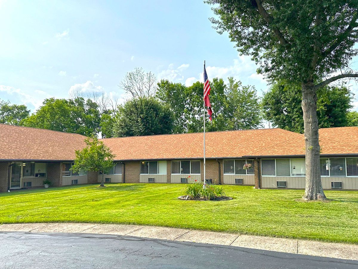 A large house with a large lawn in front of it and a flag pole in front of it.