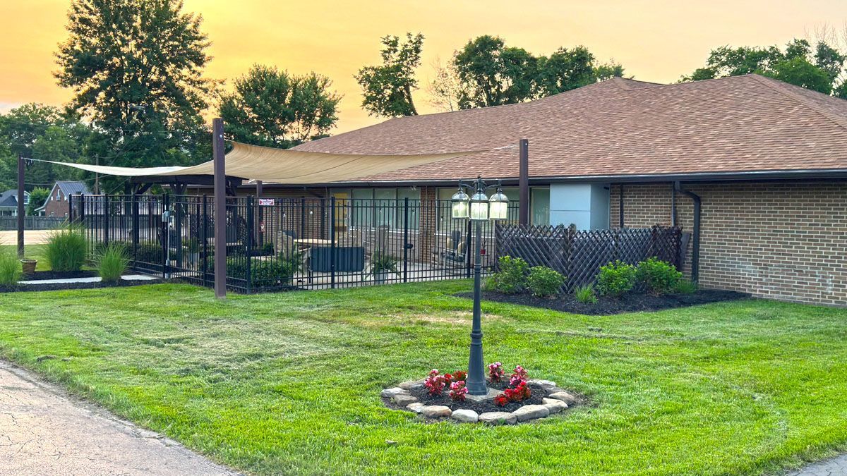 A house with a large lawn and a fence in front of it.