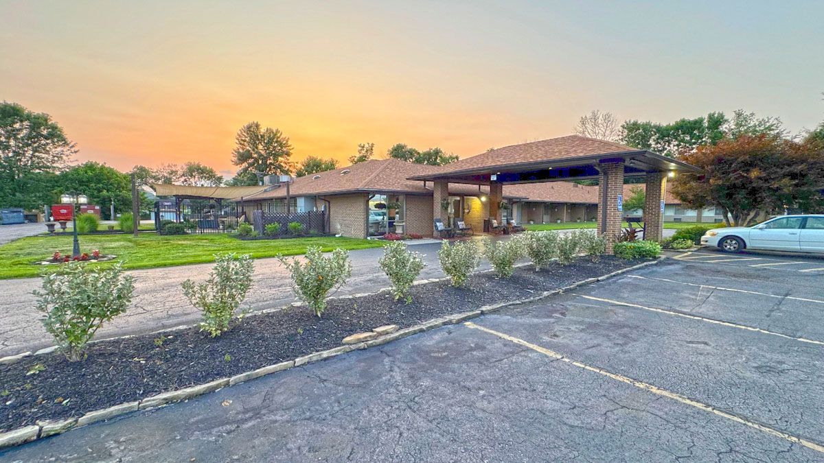 A white car is parked in front of a large building.