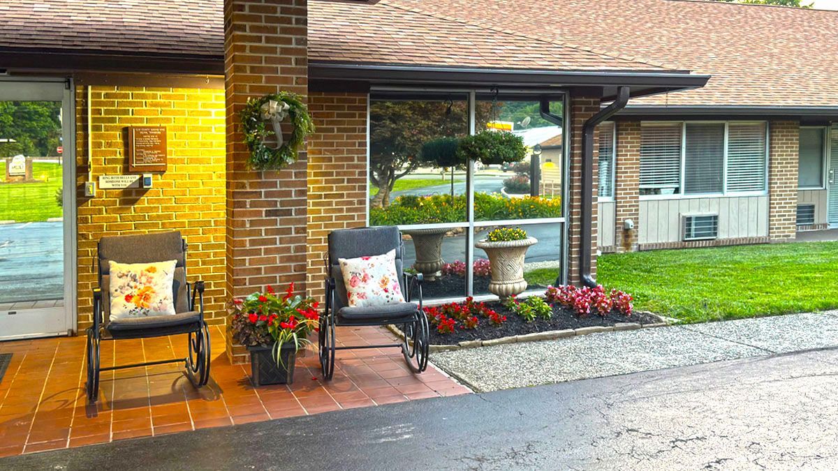 A brick house with chairs and flowers in front of it.