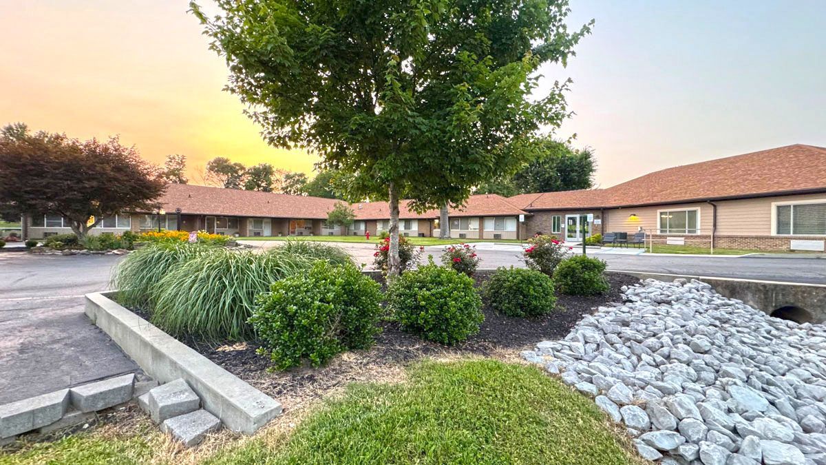 A motel with a lot of plants and rocks in front of it.