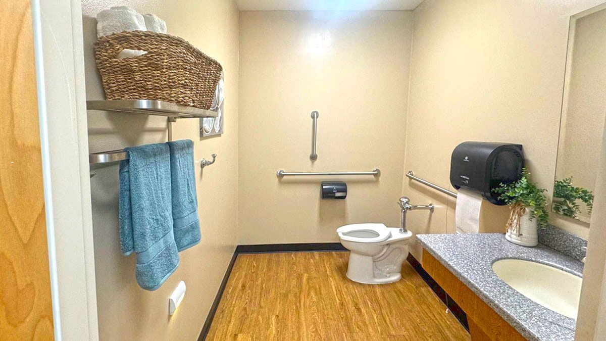 A bathroom with a toilet , sink , and towel rack.