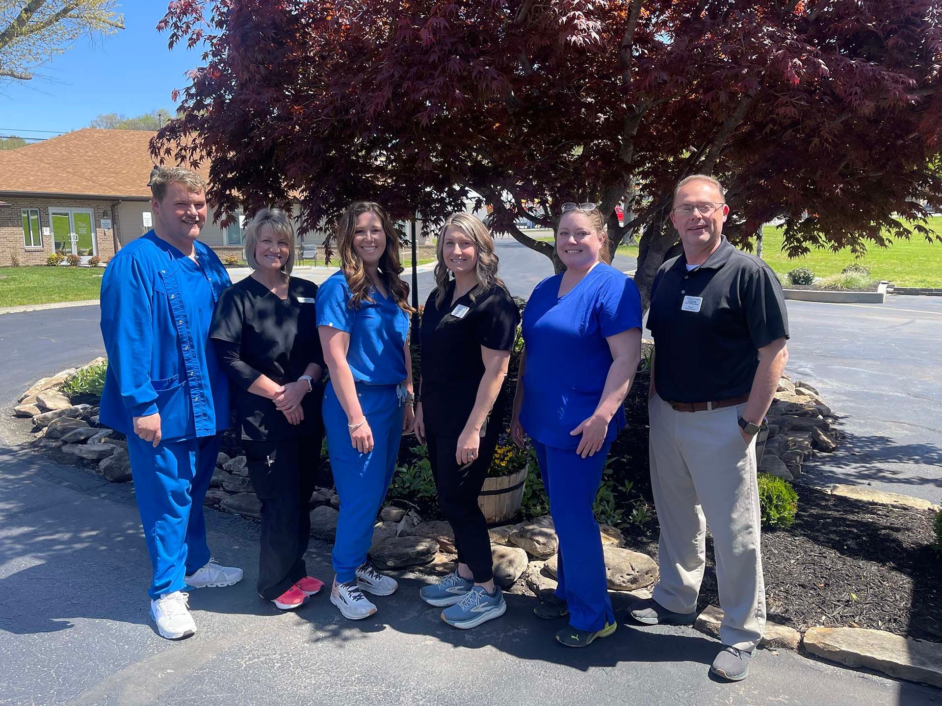 A group of people standing next to each other in front of a tree.