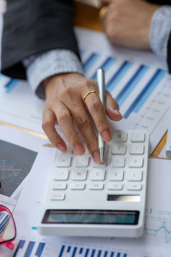 A close up of a person using a calculator with a pen.