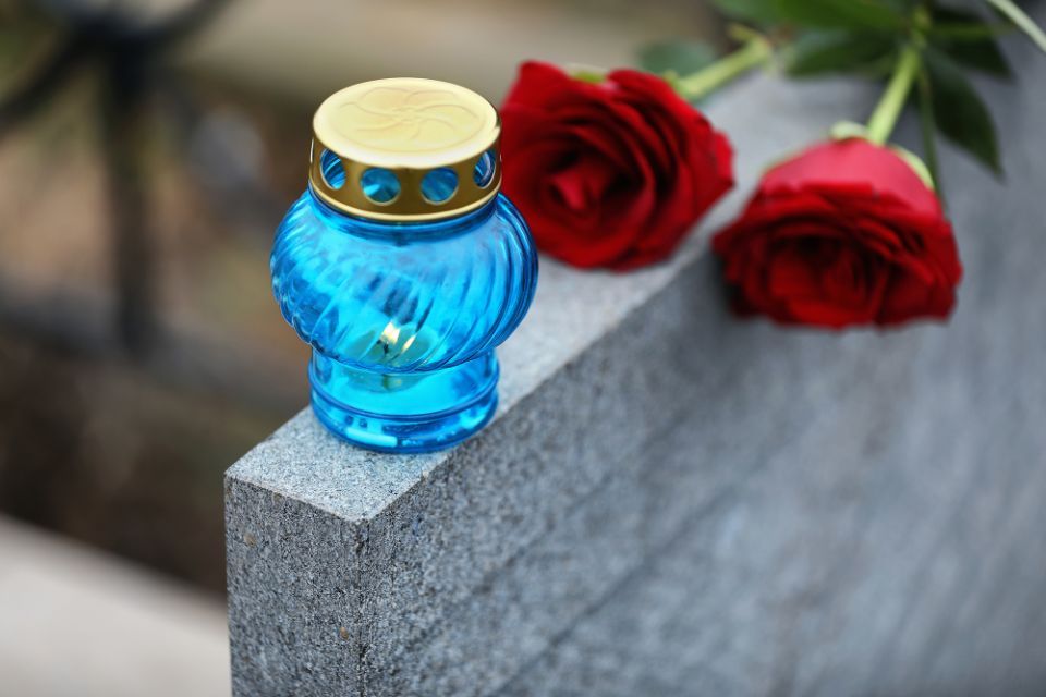 lapide con luce e rosa rossa