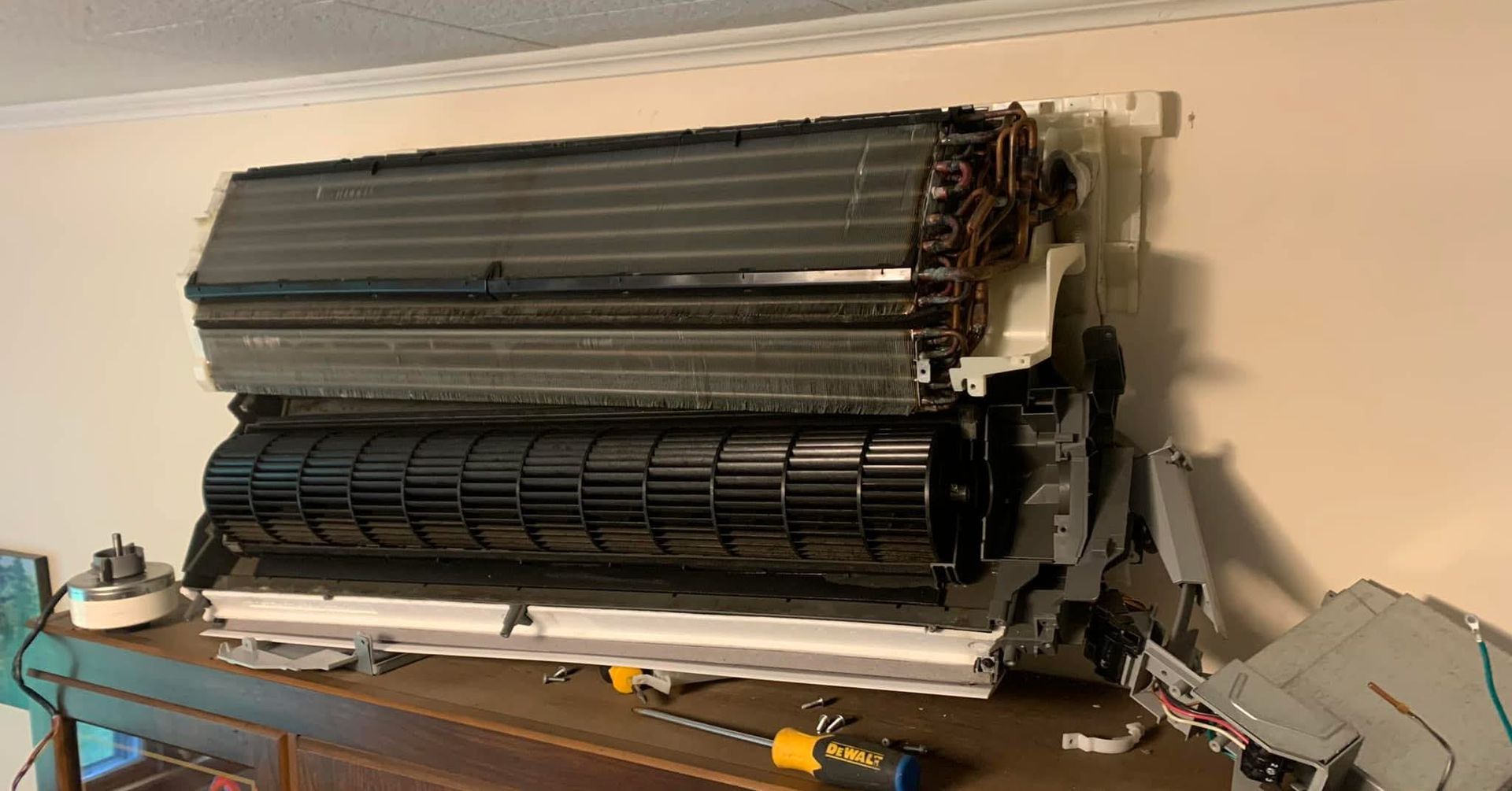 A wall-mounted air conditioner unit with its front casing removed, revealing internal components and a blower fan.