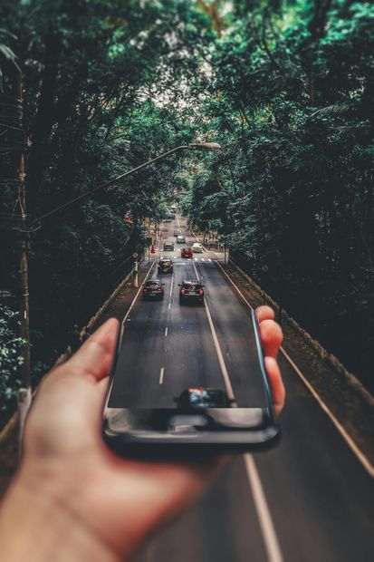 A person is holding a cell phone in their hand and taking a picture of a highway.