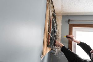 A man is working on a wall with a screwdriver.