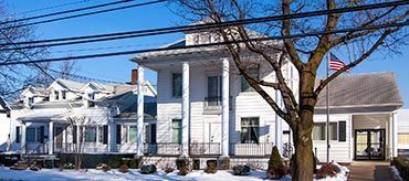 White building with large columns and an American flag. Winter scene with snow.