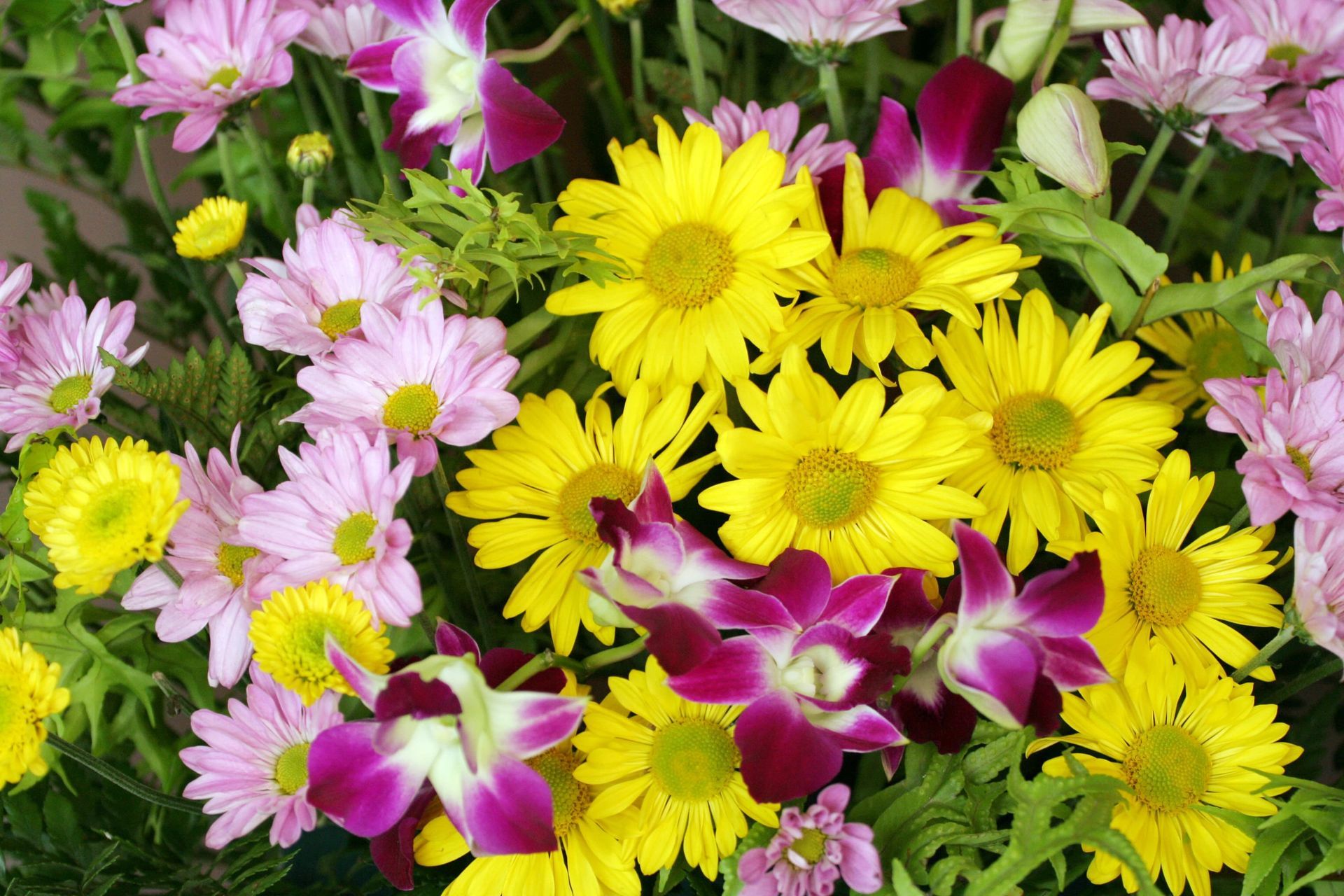 People arranging flowers on a wooden table, wearing aprons.