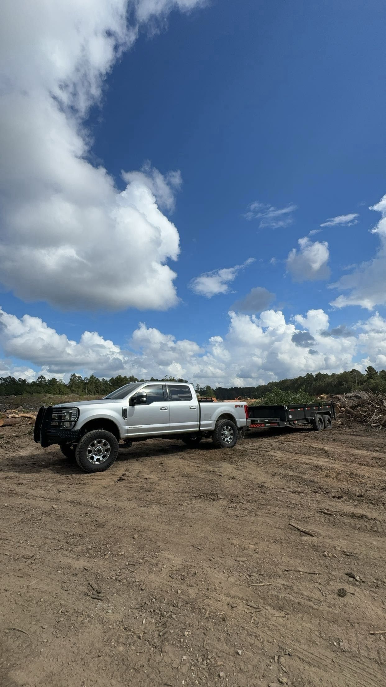 Woman in straw hat smiles, holding wine glass near a lake.
