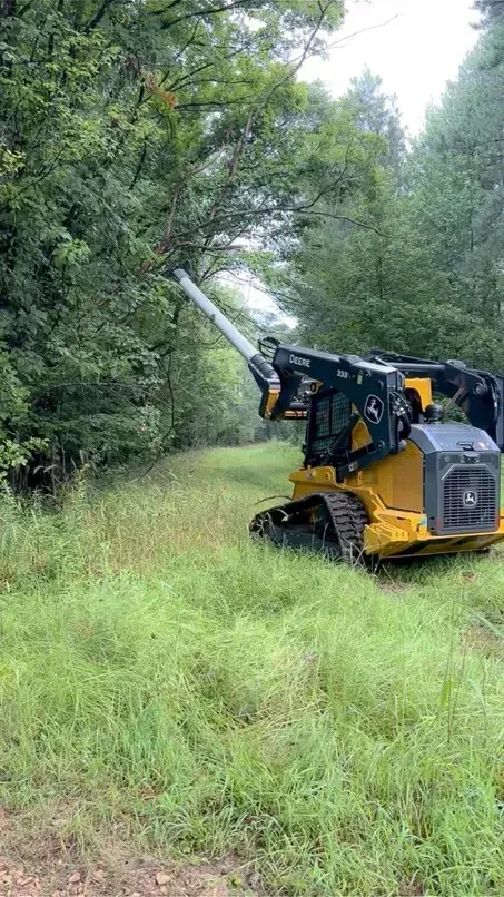 Woman in straw hat smiles, holding wine glass near a lake.
