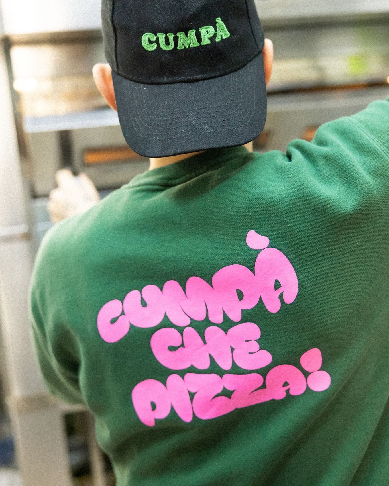 Persona che indossa una felpa verde e un berretto con la scritta 