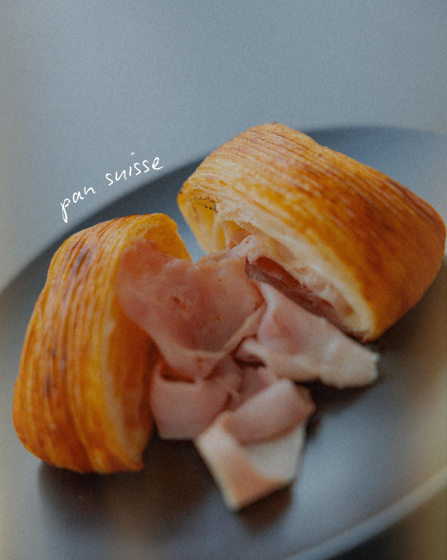 Pan Suisse con prosciutto su un piatto scuro.