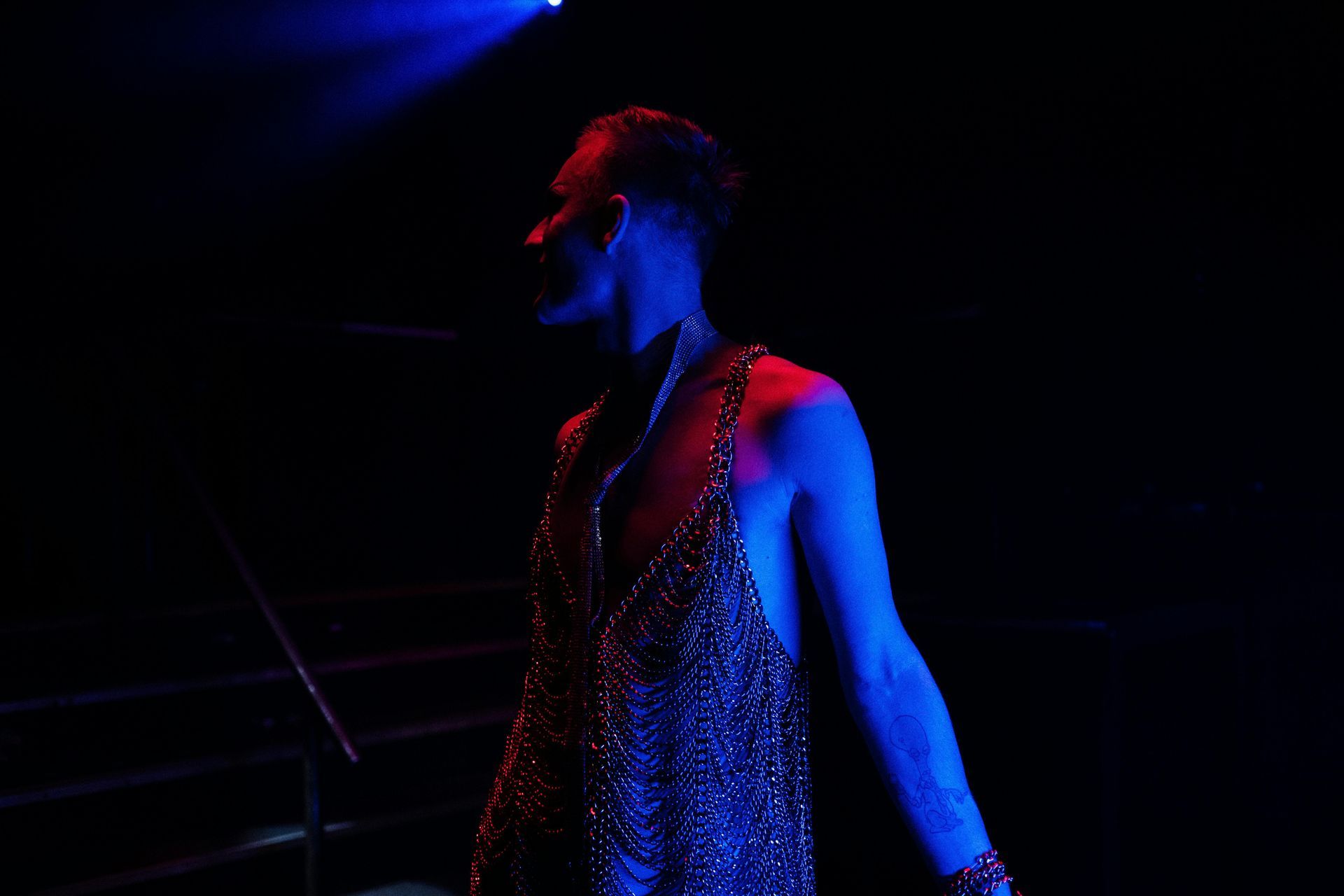 A man is standing in a dark room with blue lights behind him.