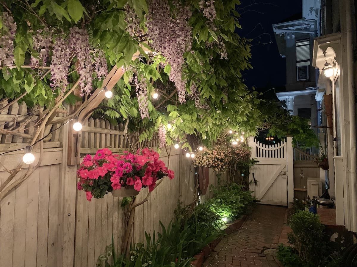 A wooden fence with flowers and lights on it at night.