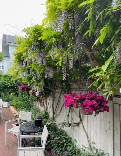 A backyard with a fence , chairs , a table and flowers.