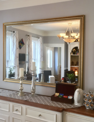 A large mirror is hanging on a wall above a dresser