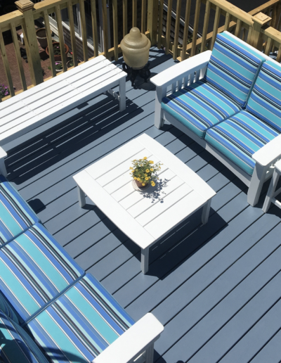 A deck with blue and white striped furniture and a white table