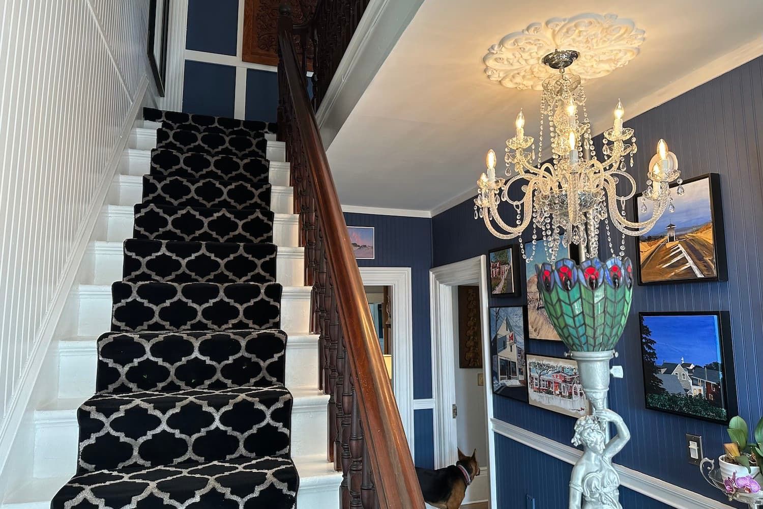 A staircase with a black and white carpet and a chandelier.