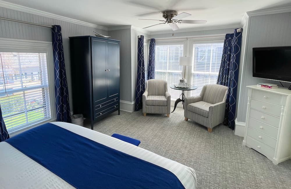 A bedroom with a bed , chairs , dresser and television.