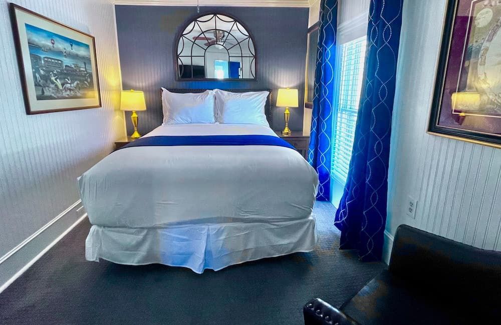 A hotel room with a king size bed and blue curtains.