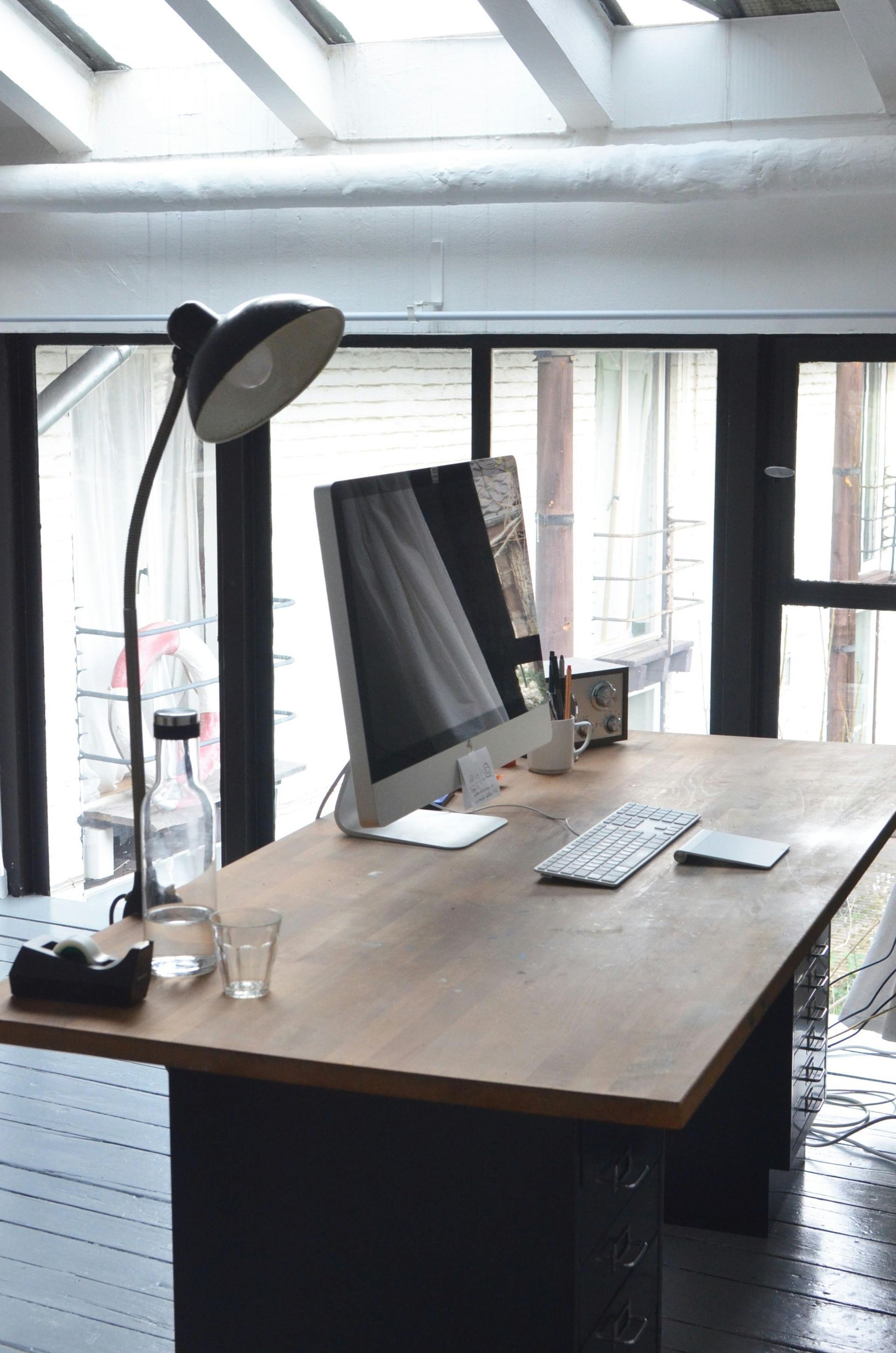Desk with computer, lamp, and window in a loft office.