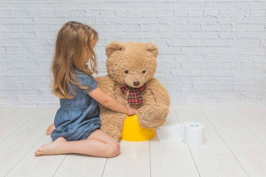 Little girl potty training a teddy bear