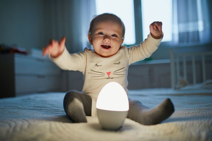 Smiling baby sitting with a Nightlight