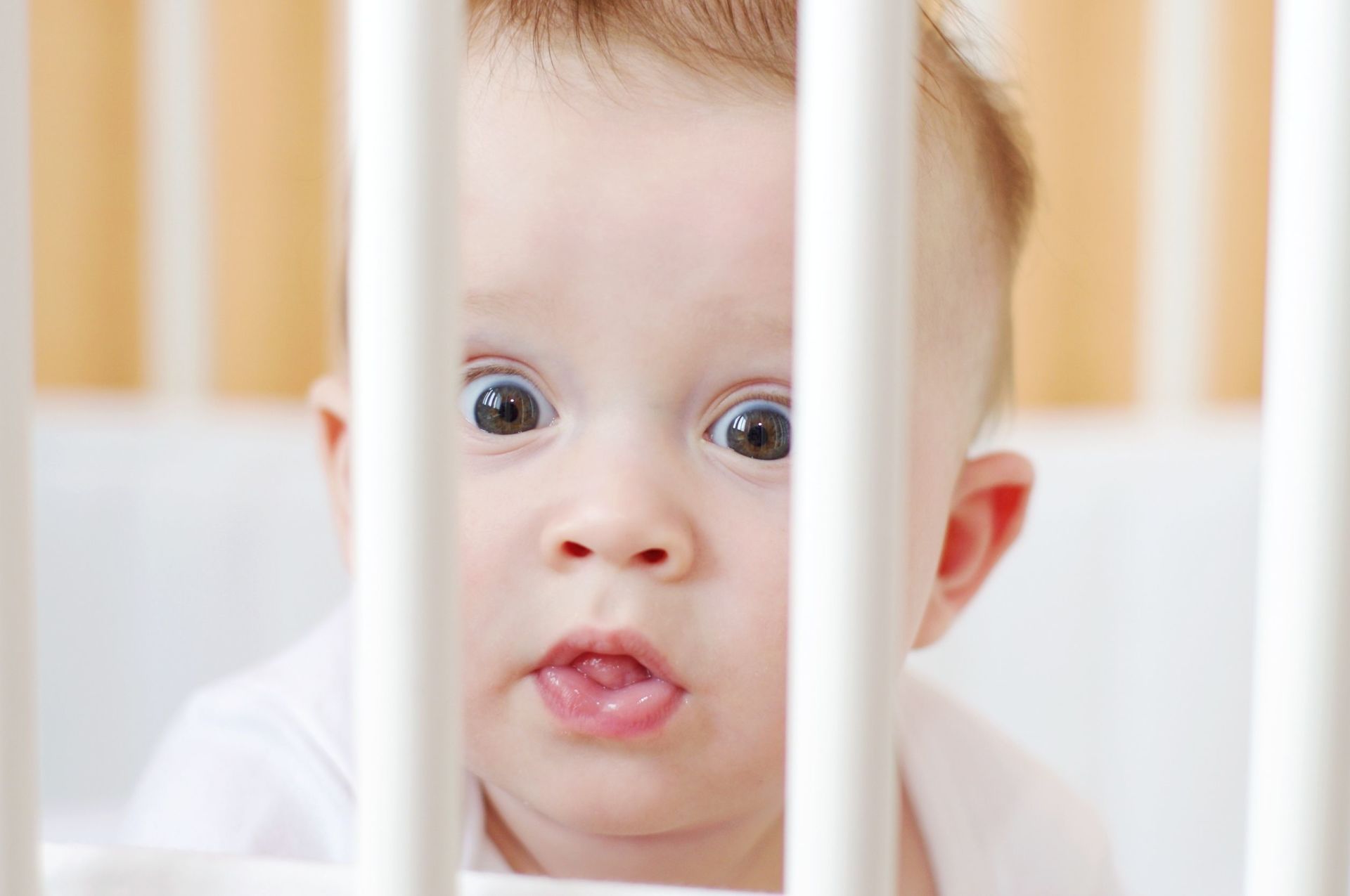 Baby in a crib with a surprised look on it's face