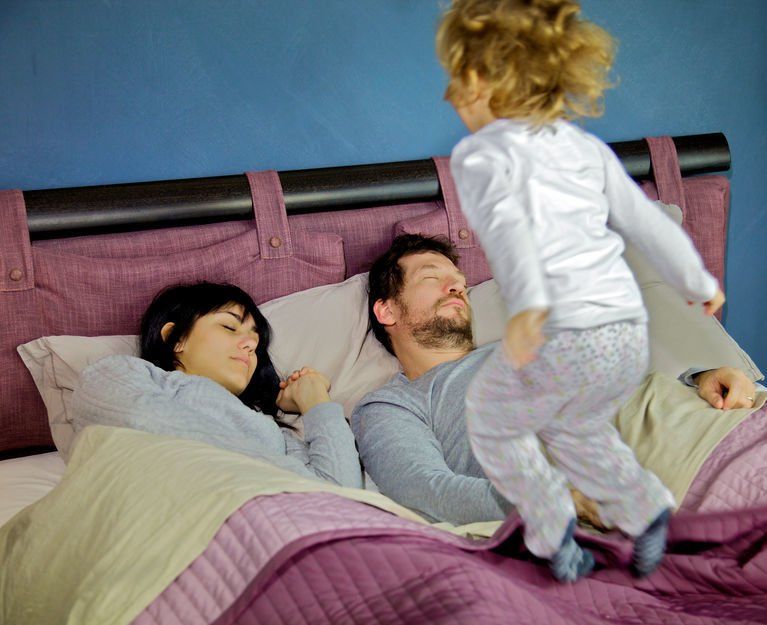 Kid jumping on the bed while parents sleep