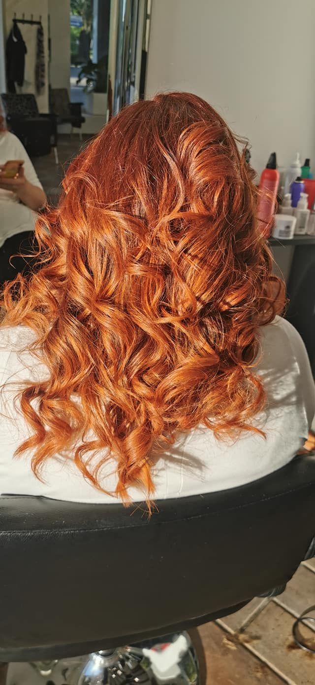 Una donna con i capelli rossi è seduta su una sedia in un salone.