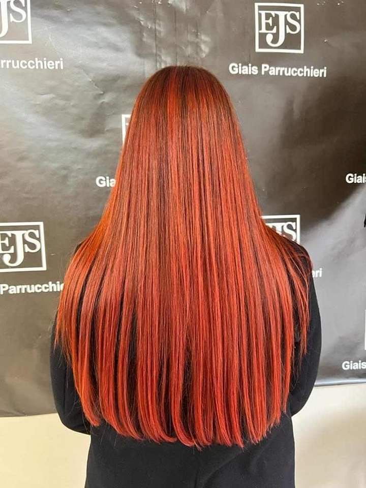 Una donna con lunghi capelli rossi è in piedi davanti a un cartello.