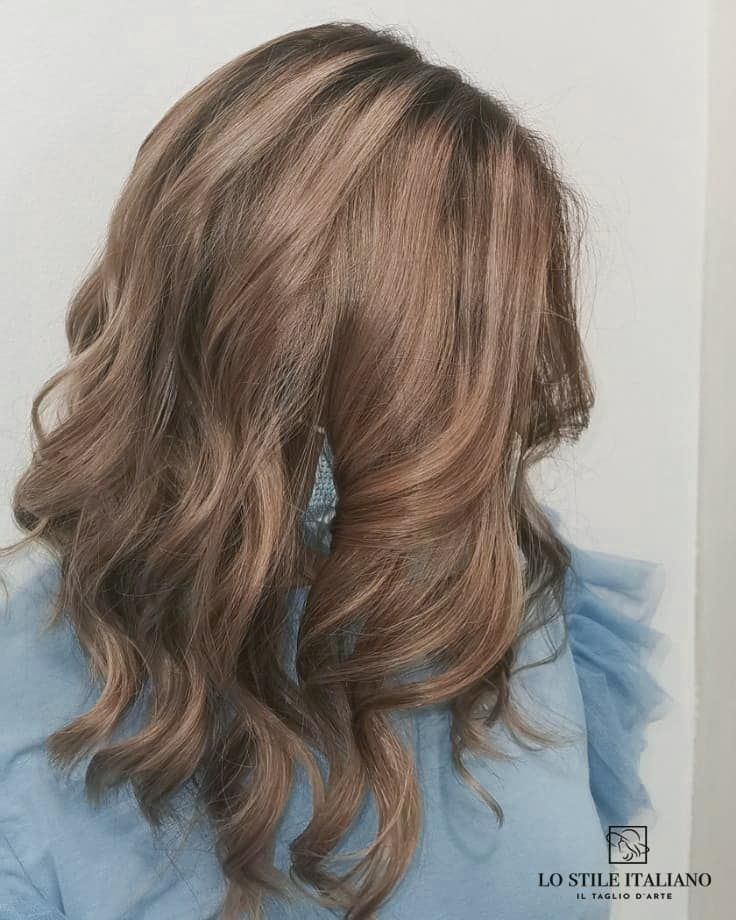 Una donna con lunghi capelli castani indossa una maglietta blu