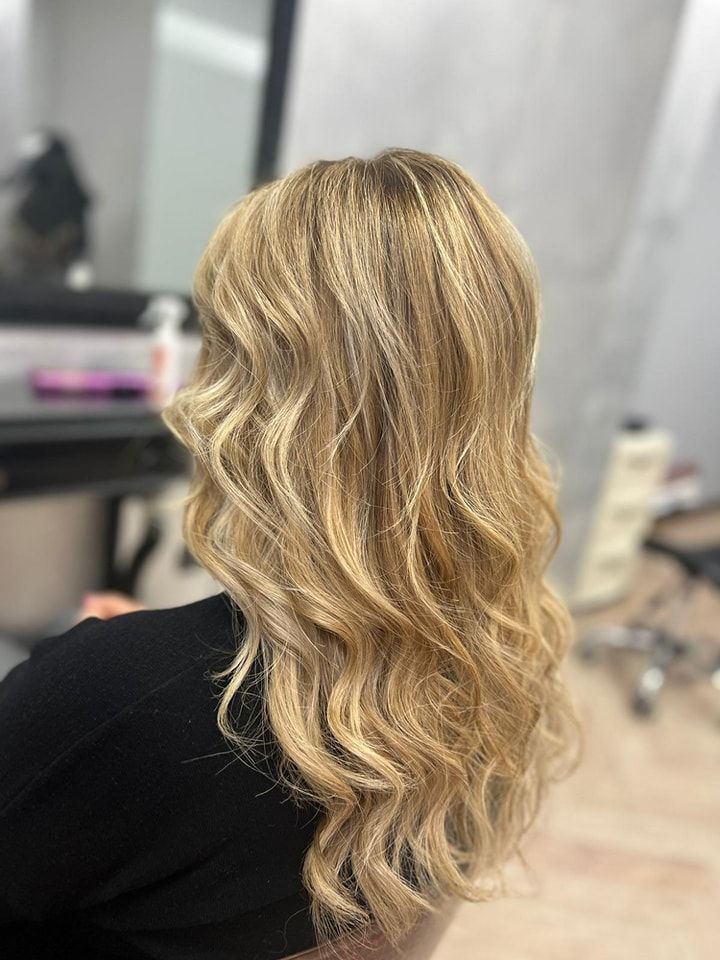 Una donna con lunghi capelli biondi è seduta su una sedia in un salone.