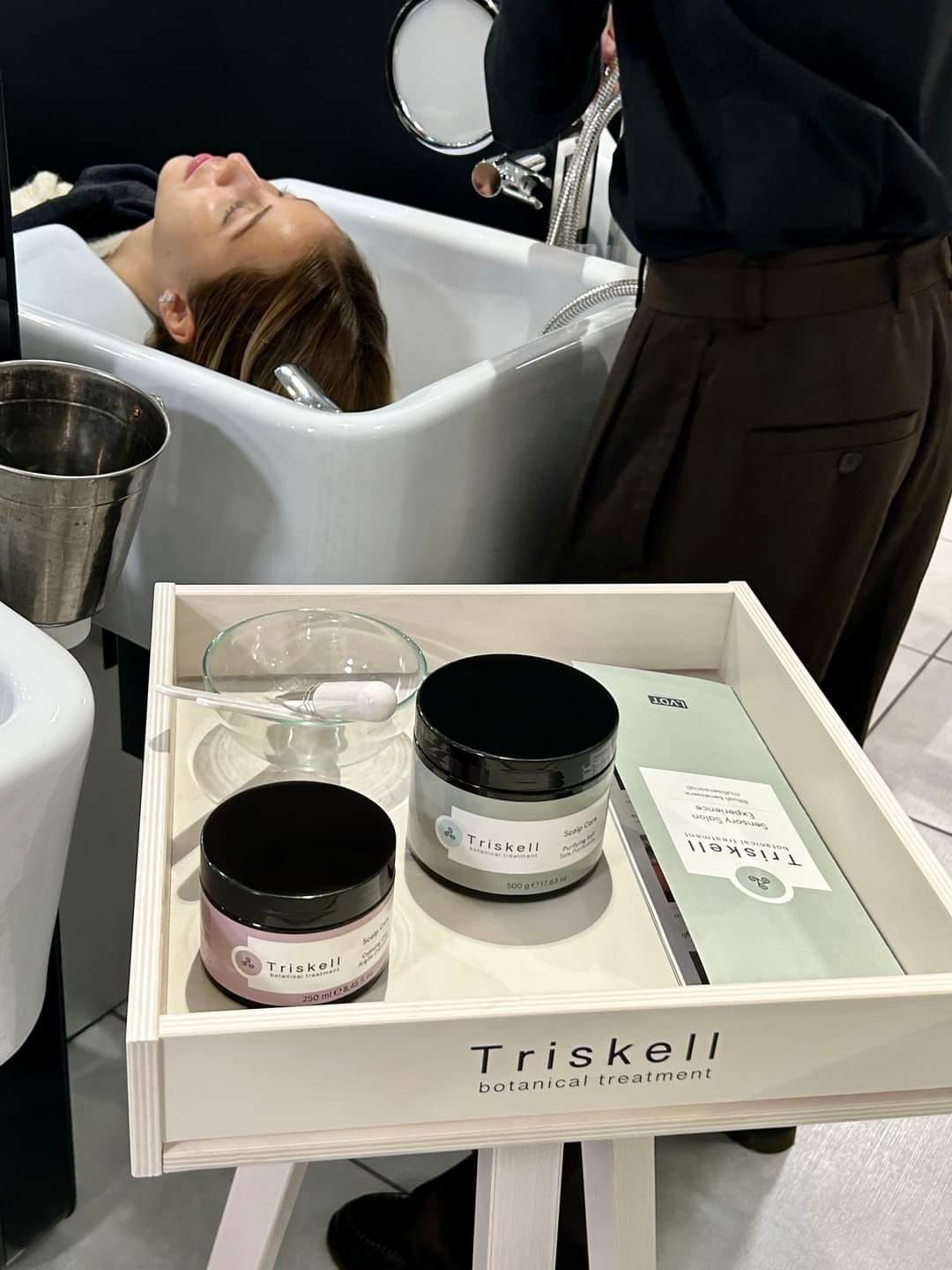 Una donna si sta lavando i capelli nel lavandino di un salone.