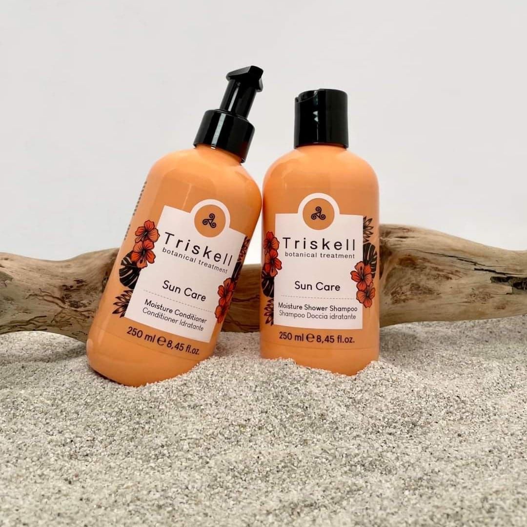 Due bottiglie di shampoo e balsamo sono appoggiate su un mucchio di sabbia.