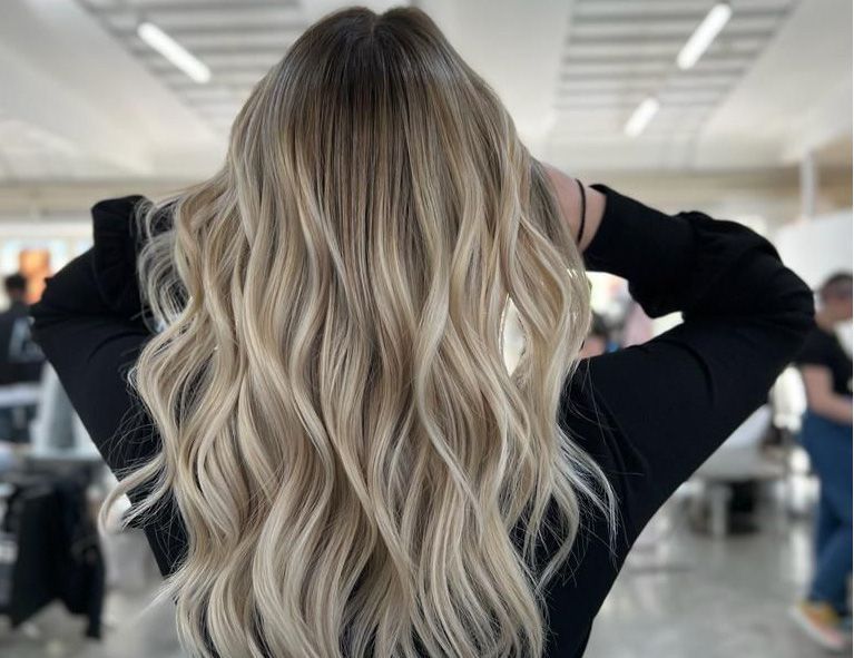 Una donna con lunghi capelli biondi indossa una camicia nera.