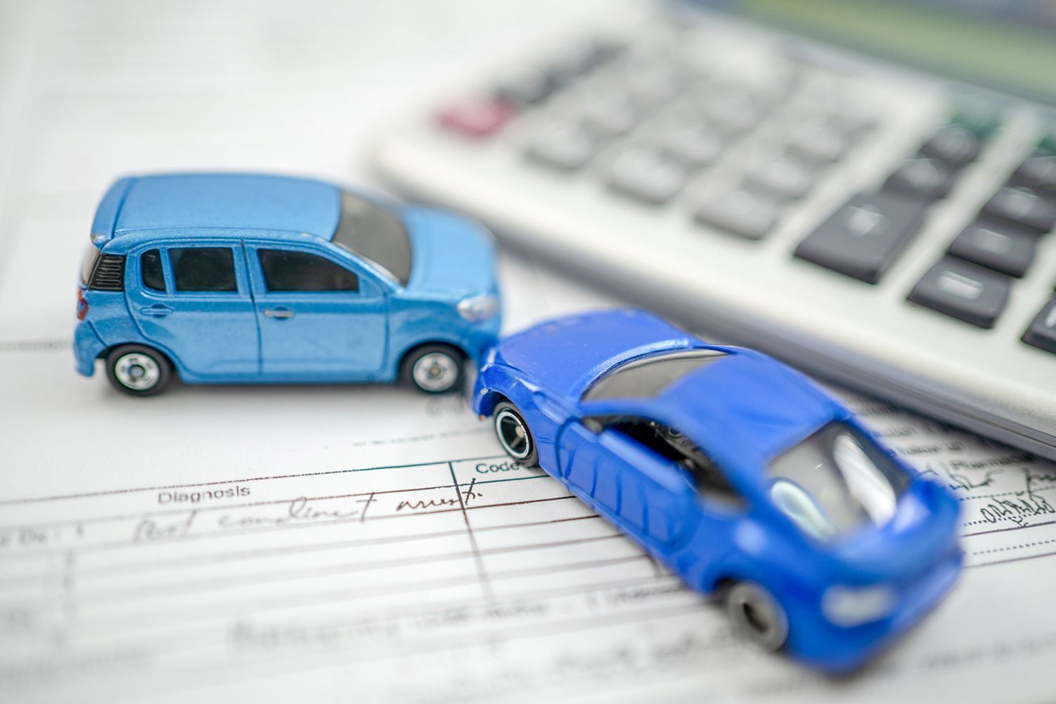 Two blue toy cars near a calculator on a document with text.