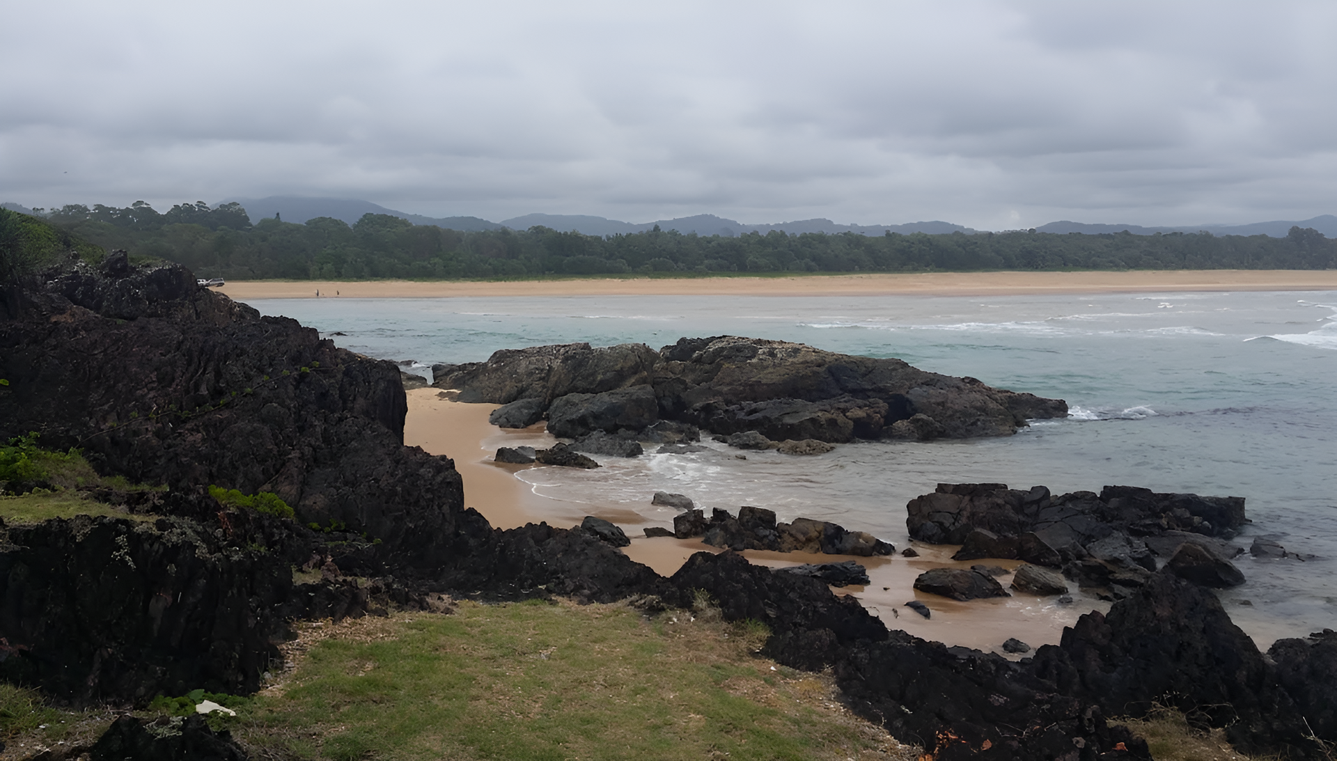 Rocky coastline, sandy beach, overcast sky — Stuart Pearce Electrical In Coffs Harbour, NSW