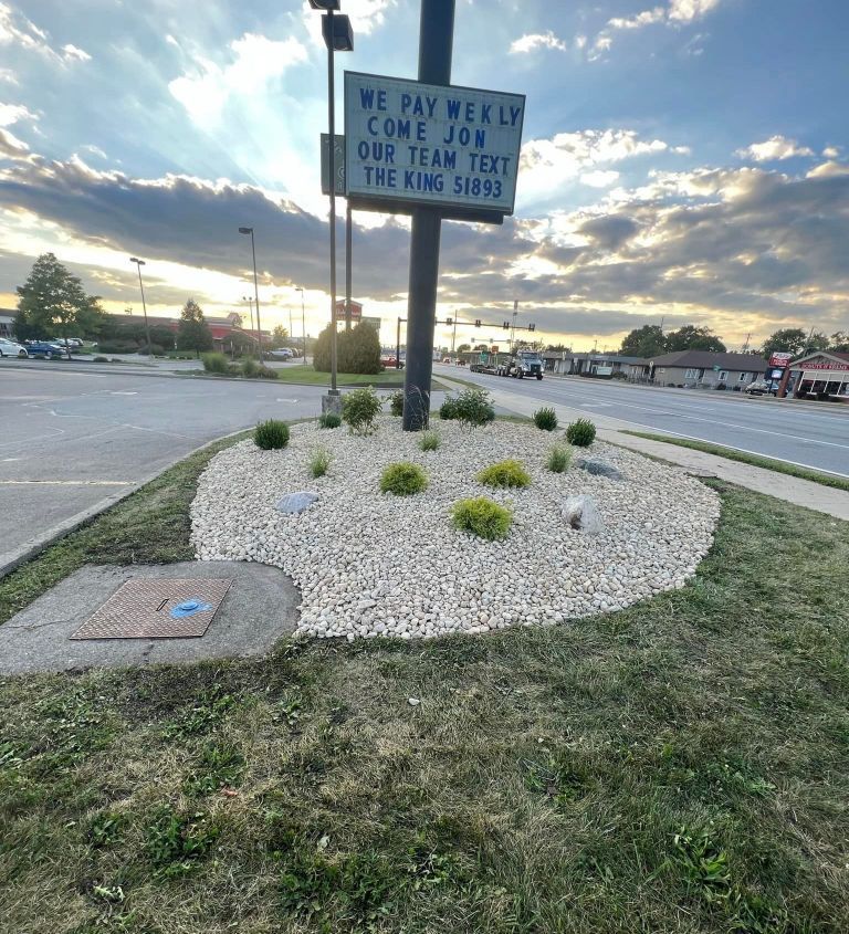 A lawnmower cuts a clean, straight path through thick green grass, showing a contrast between trimmed and untrimmed areas.