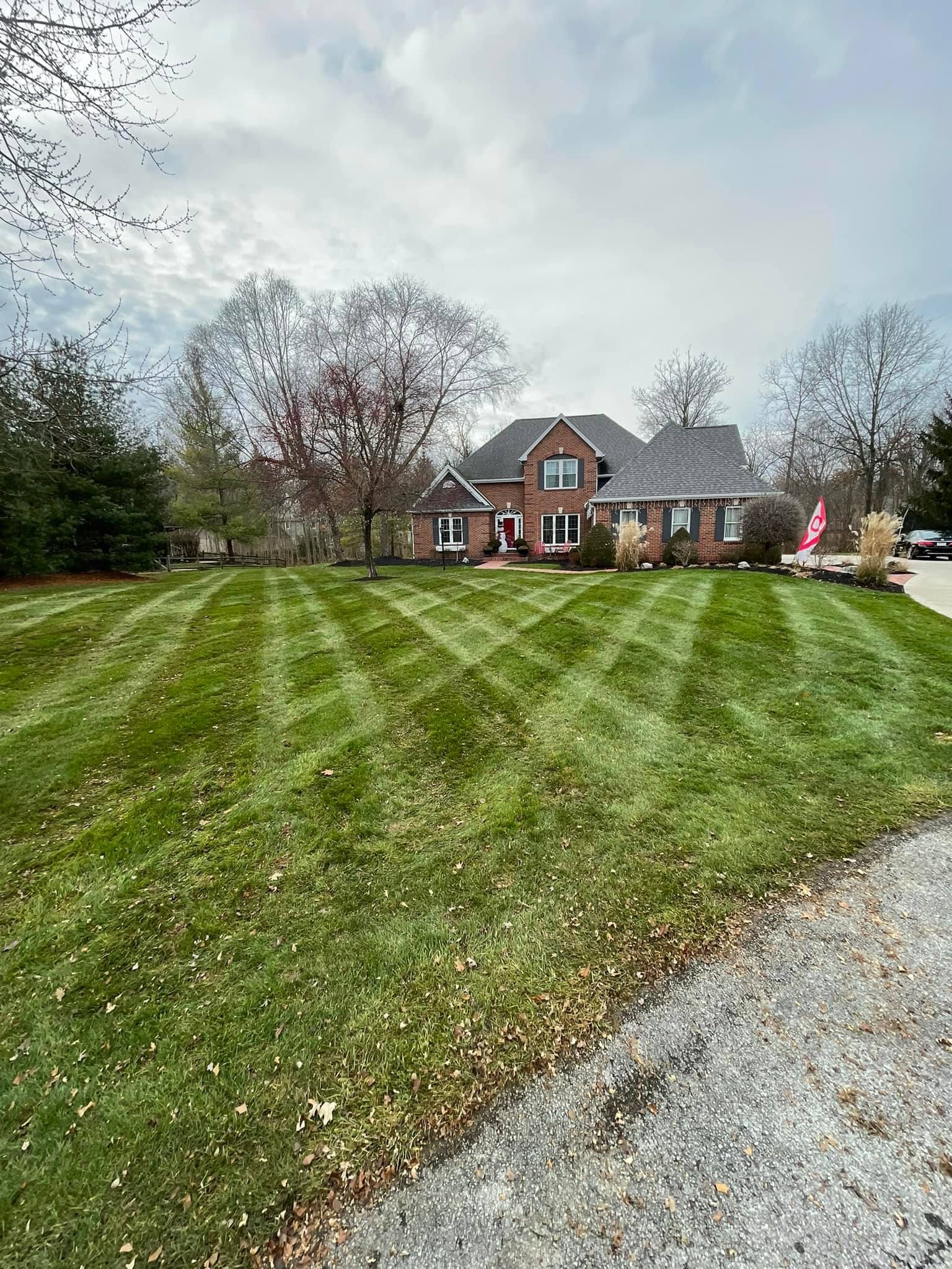 A large brick house with a striped lawn. The sky is overcast.