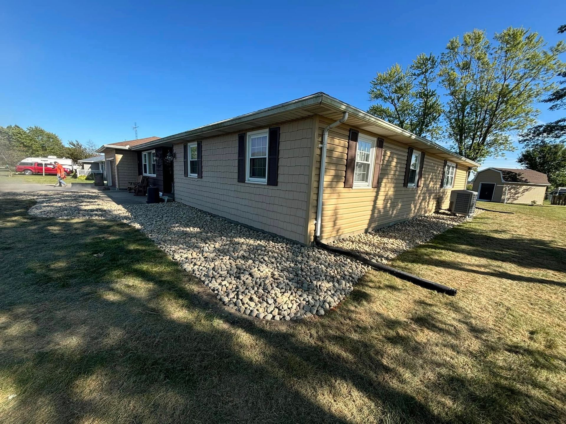 Tan brick building with rock landscaping and dark shutters under a blue sky.
