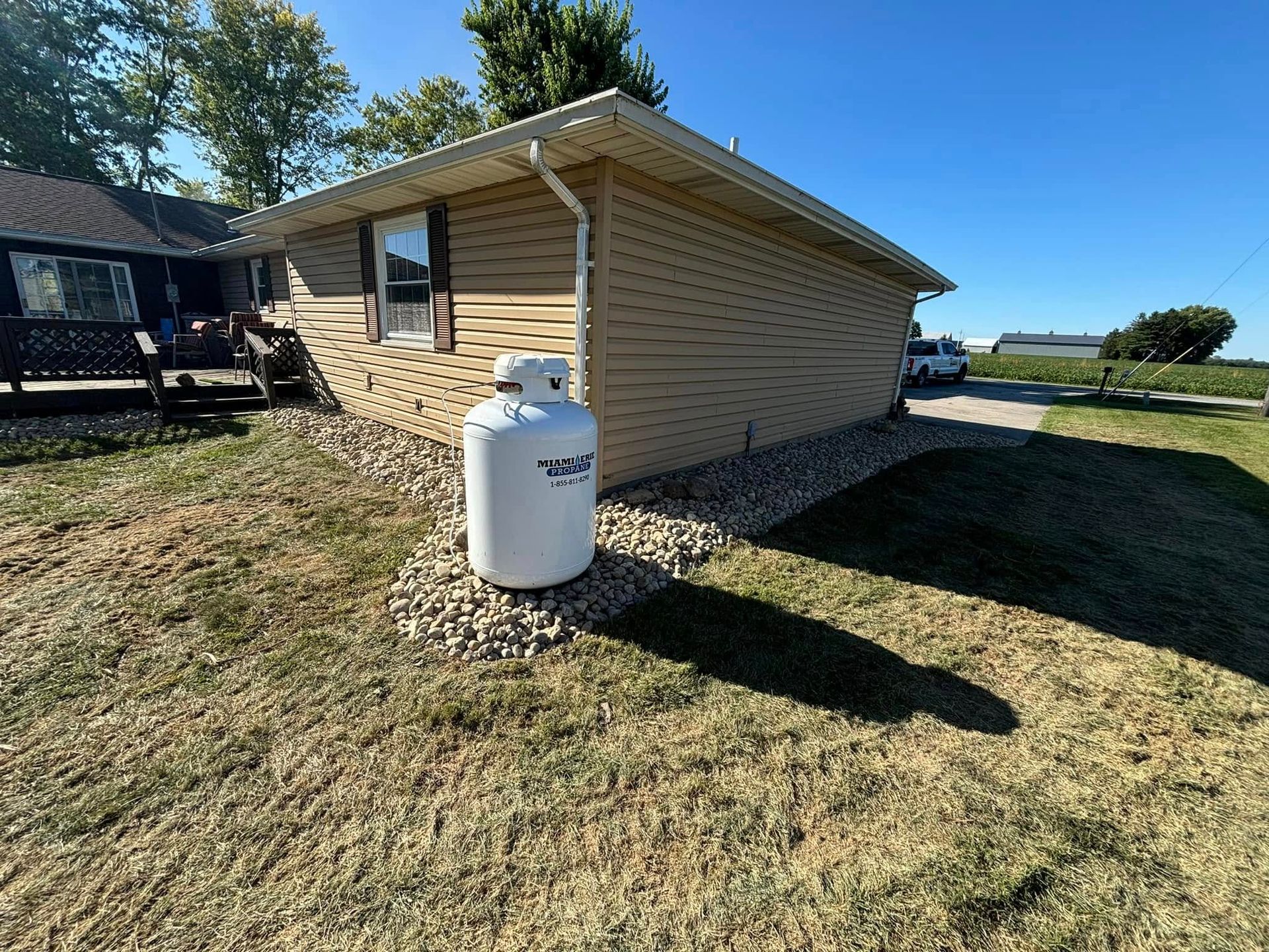 A propane tank sits in front of a small building with beige siding.