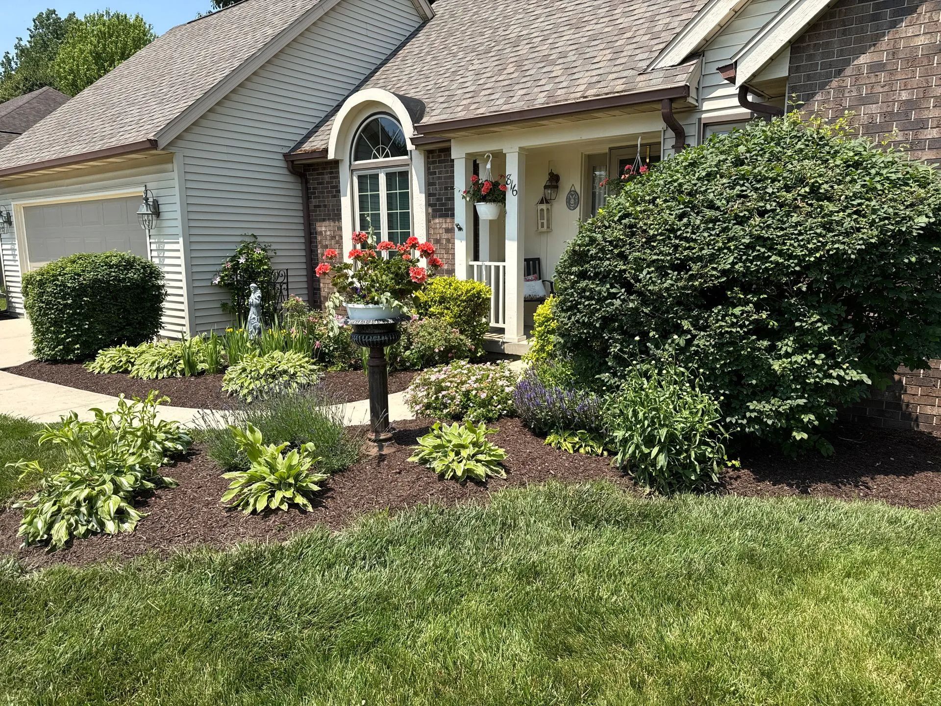 A lawnmower cuts a clean, straight path through thick green grass, showing a contrast between trimmed and untrimmed areas.