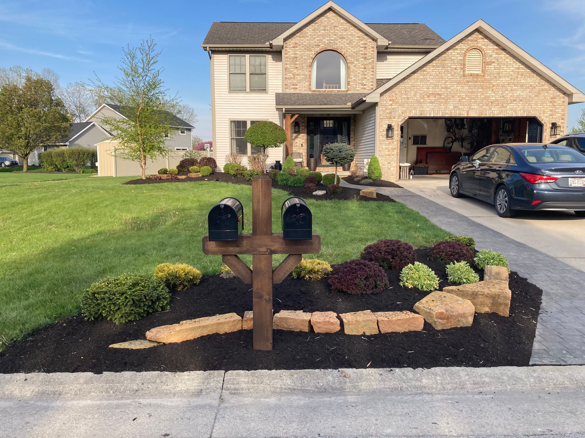 Mailbox with flower bed in front of a two-story house with a garage.