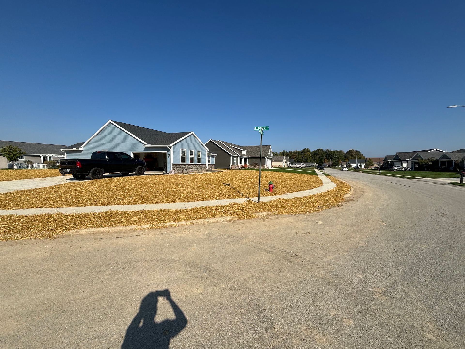 New houses with gravel roads and a light blue sky on a sunny day.