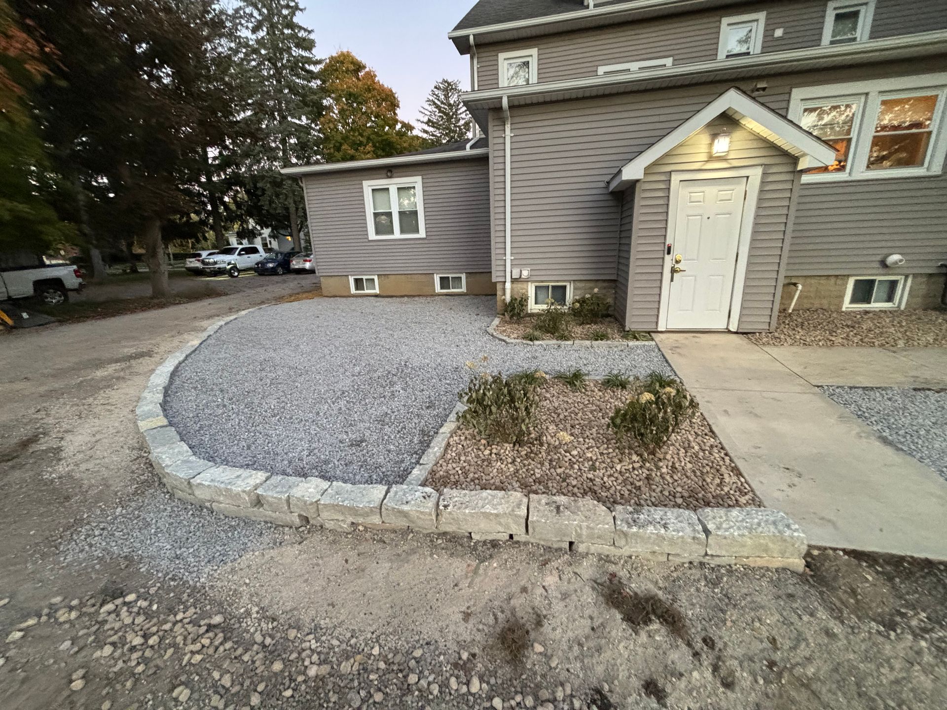 Gravel landscaping with a stone retaining wall in front of a two-story house.