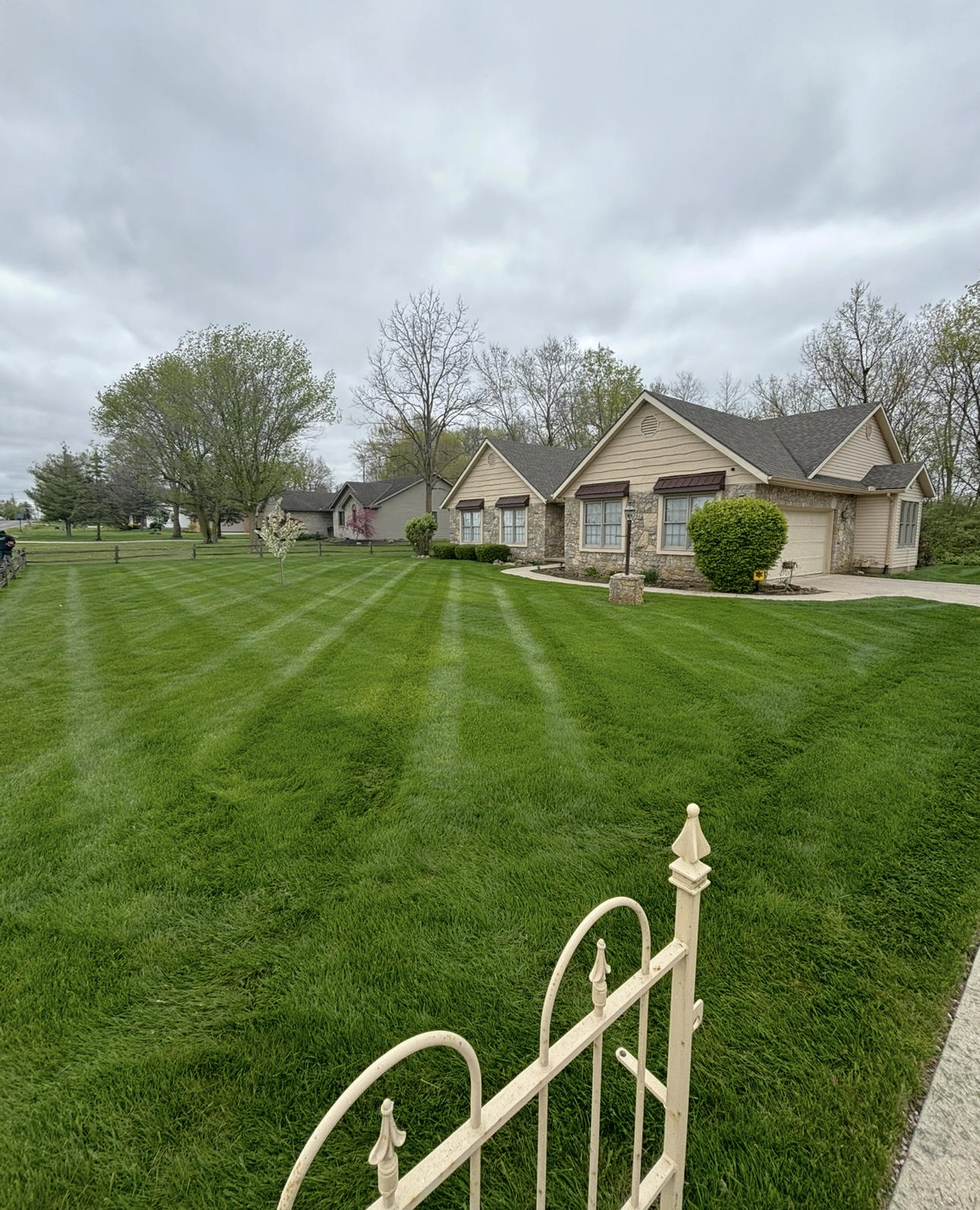 Well-manicured lawn with striped mowing pattern in front of a house on an overcast day.
